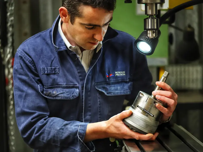 Engineer inspecting a machined metal component at a milling machine