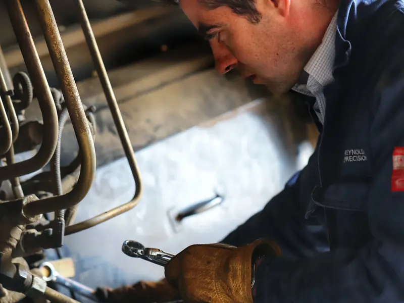 Engineer using a spanner to repair the underside of agricultural machinery