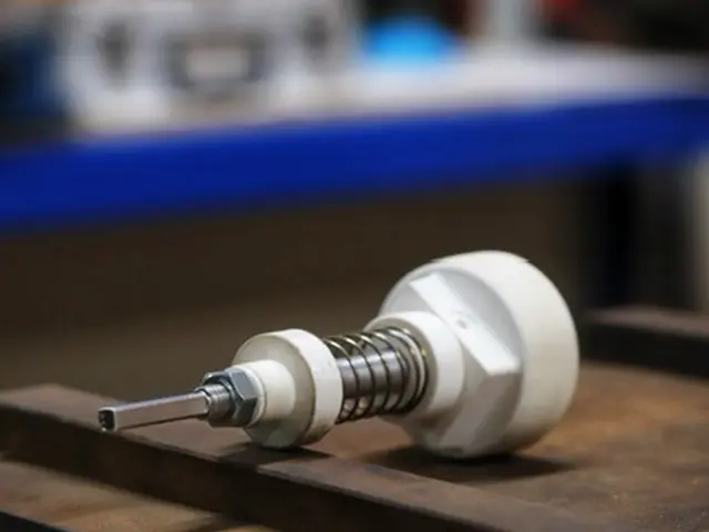 3D printed prototype assembly with metal spring on a workshop bench