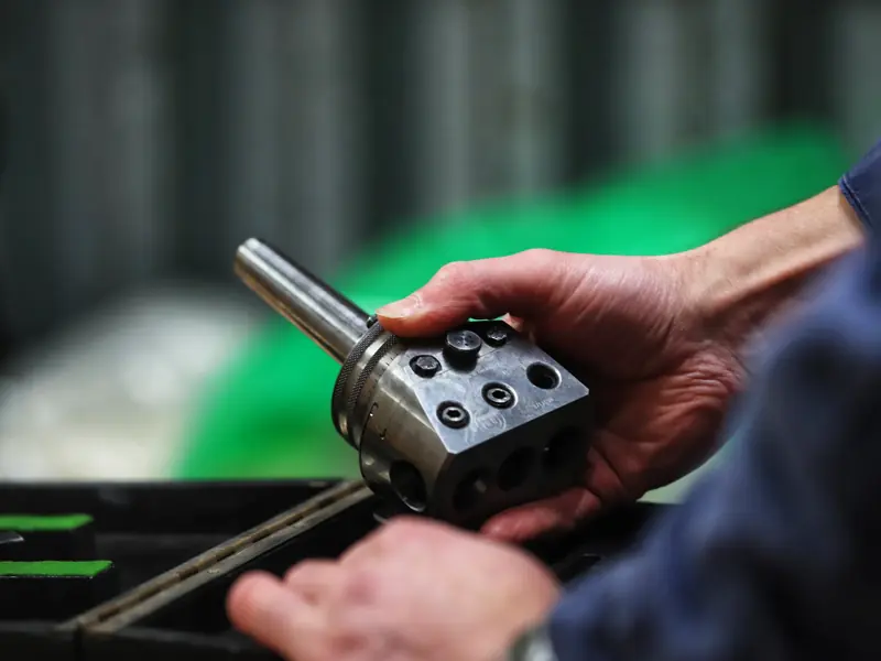 Close-up of hands holding a machined boring head in a workshop
